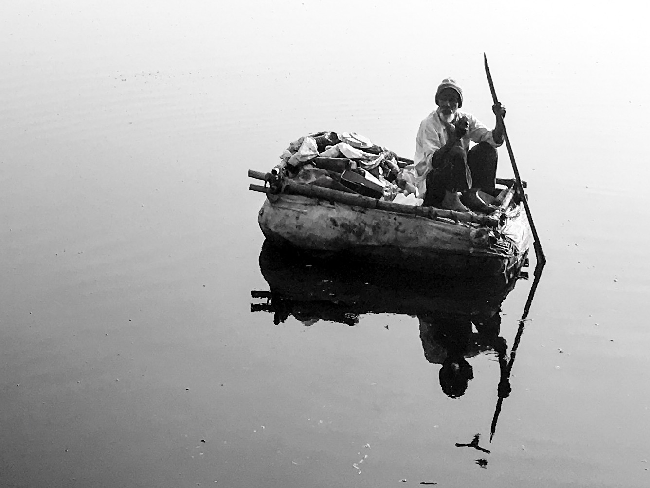 A person in a small boat reflected in still water